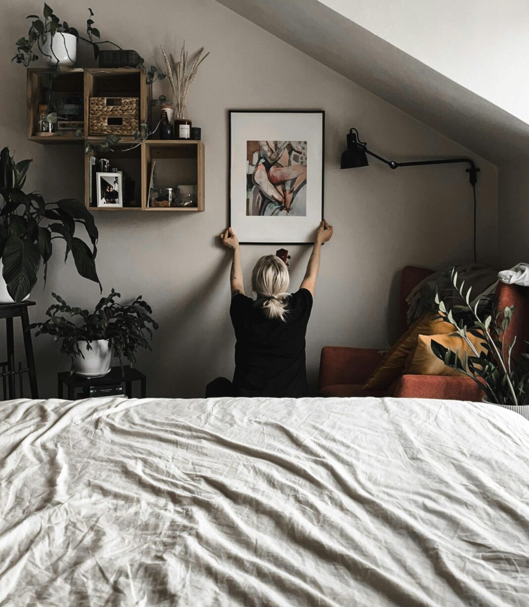 Woman Hanging a Painting in her Bedroom